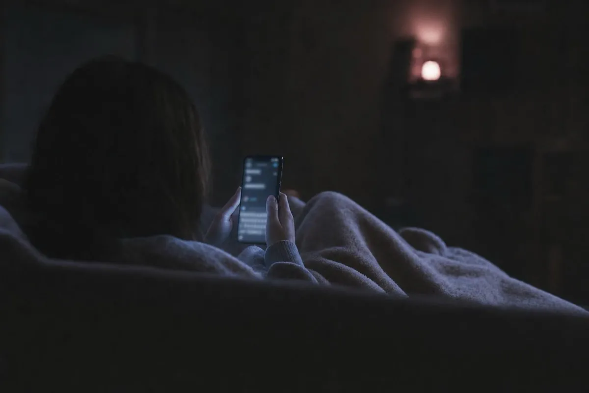 Someone under a blanket on a sofa at night, typing into TasteRay on their phone